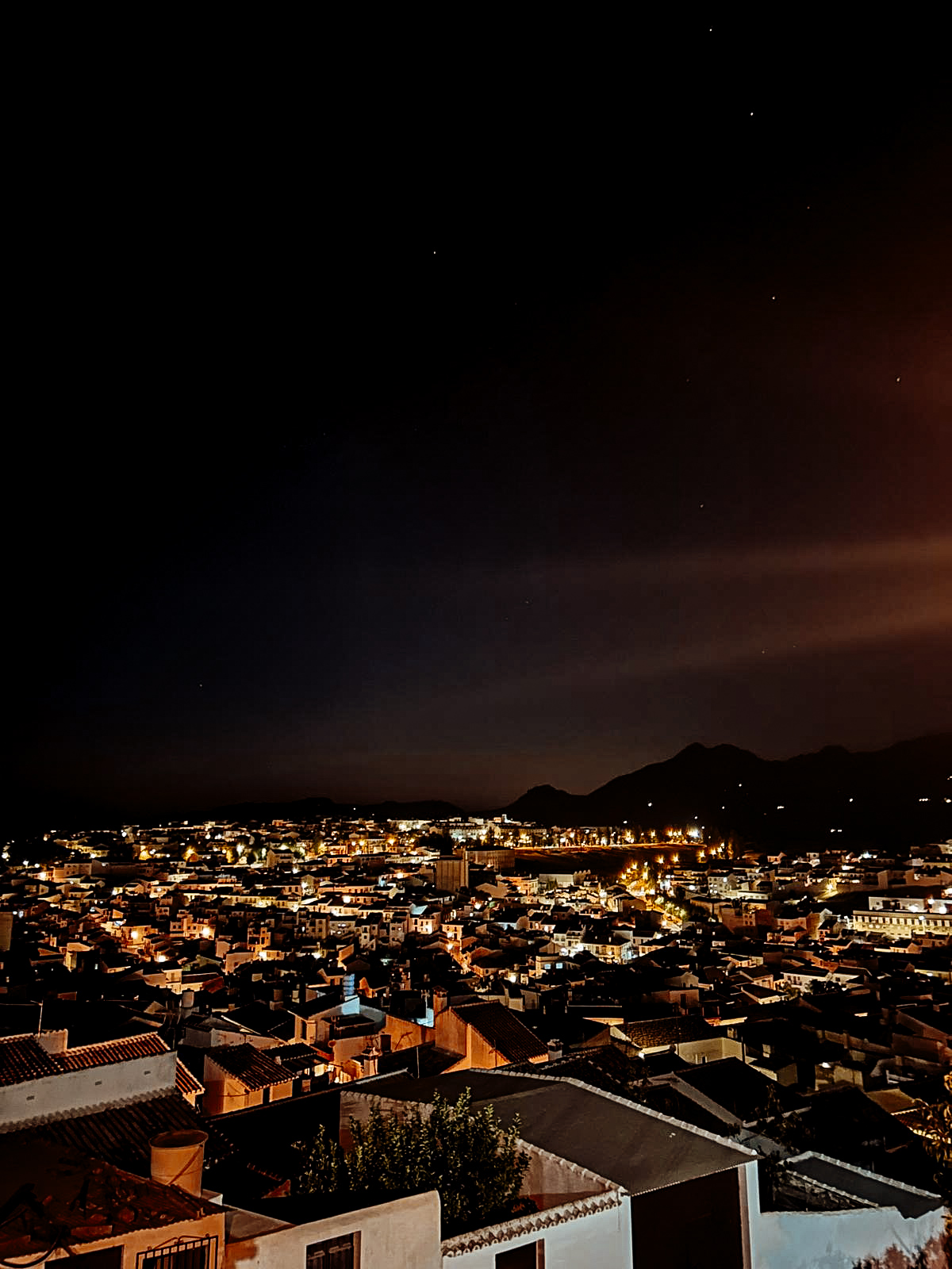 Colmenar at night, twinkling lights with the mountains in the distance